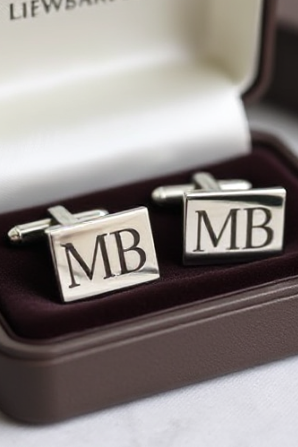 Sleek silver cufflinks engraved with his initials, resting inside a velvet box, ready for his next big event.