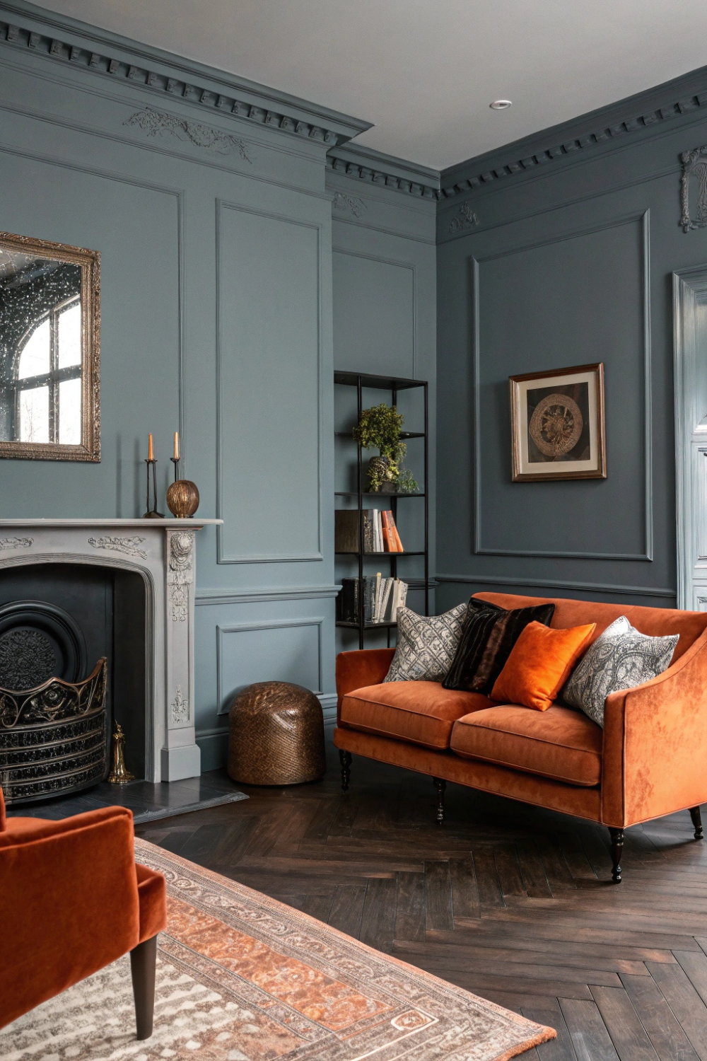 Cool gray walls with rust orange throw pillows, paired with dark wood floors and black iron accents for a bold, colonial statement.