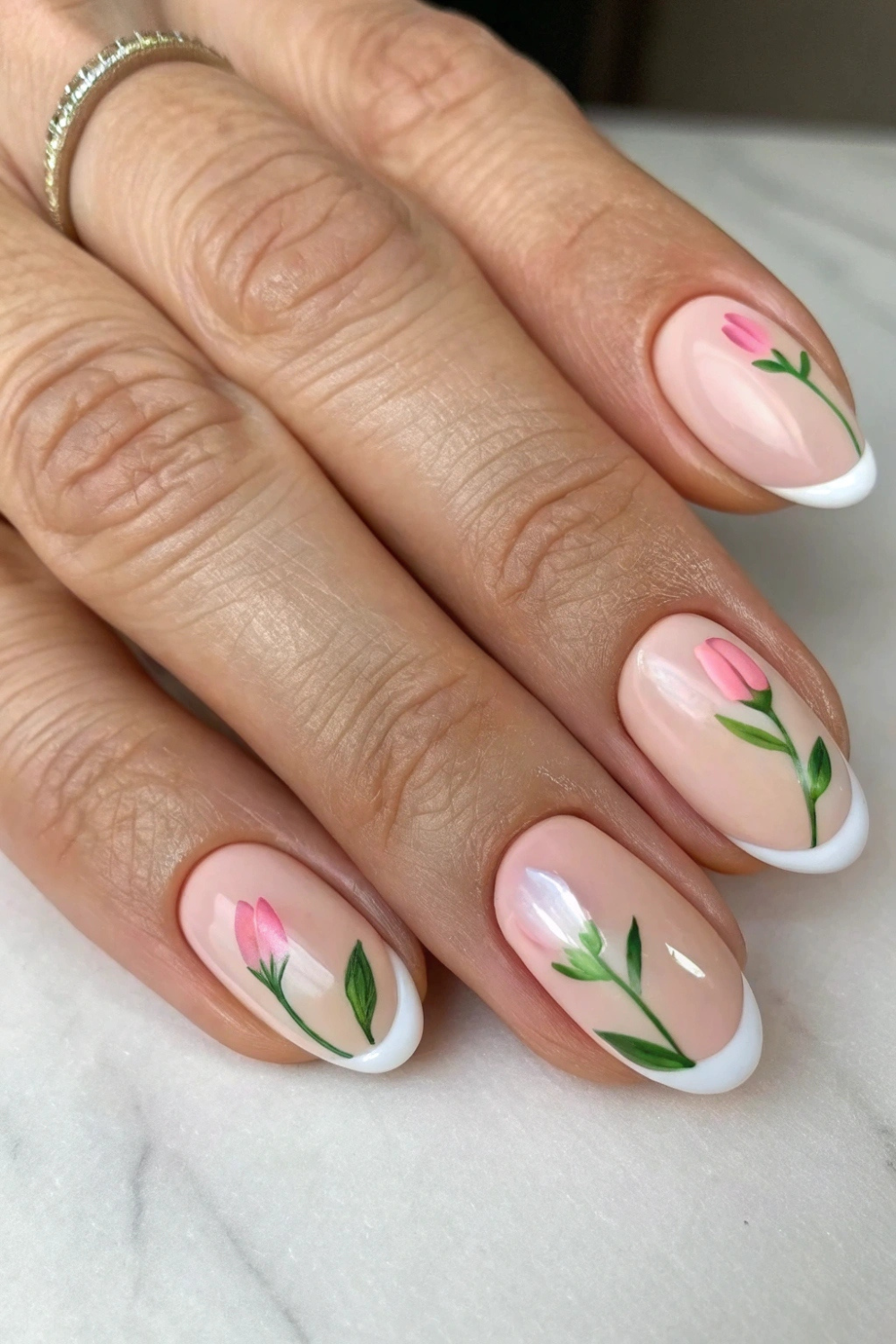A modern take on the classic French manicure, featuring soft pink or nude bases with delicate white daisy tips. Some nails have tiny green leaf details for a fresh, botanical look.